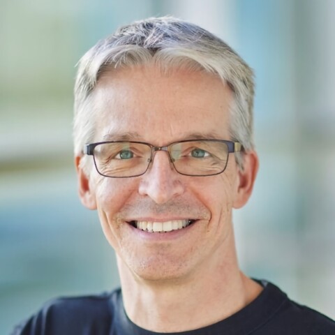 Headshot portrait of Siemens manager Dirk Didascalou in front of a blurry blue-green background.