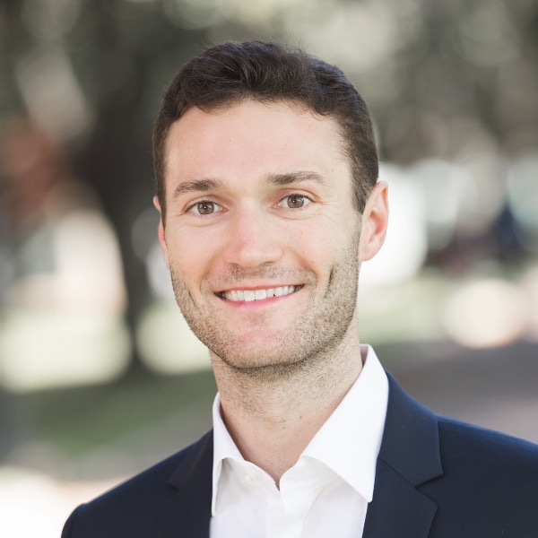 Outdoor headshot portrait of Fabien Rozzi, Make.com, in front of a blurry background.