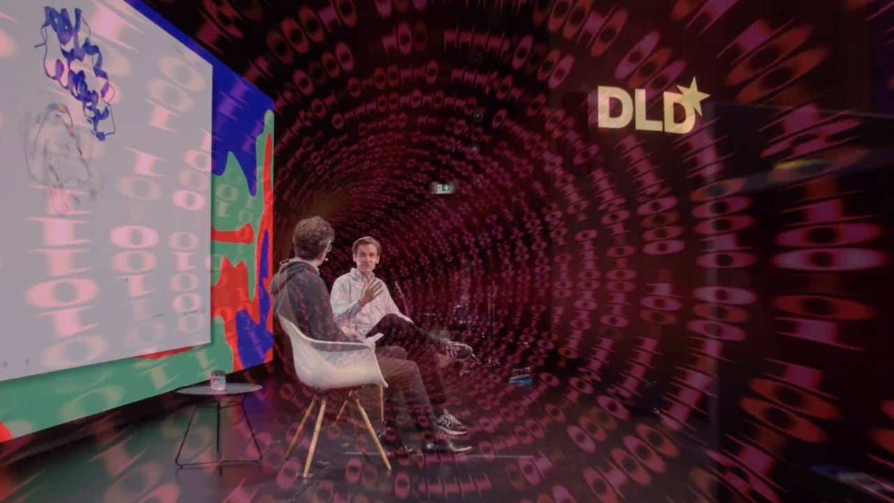 Screenshot of a conference highlight video showing speakers on stage at the DLD Future Hub conference, BAIOSPHERE day, with a light leak effect overlay.