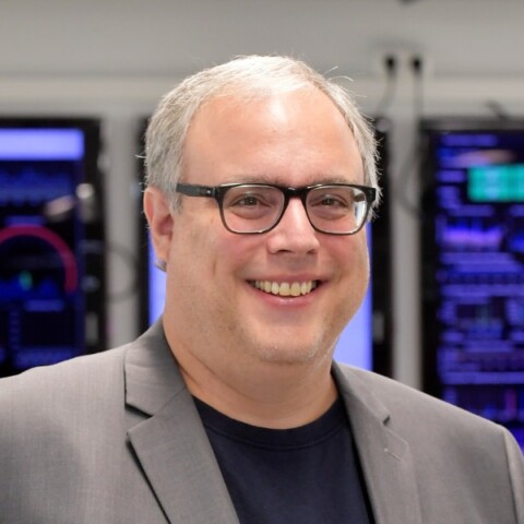 Headshot portrait of German entrepreneur Jan Ippen, CEO of Ippen Digital Media, standing in front of digital displays, smiling.