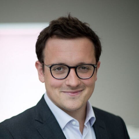 Headshot portrait of Allianz manager Ludovic Subran in front of a grey background with a white window