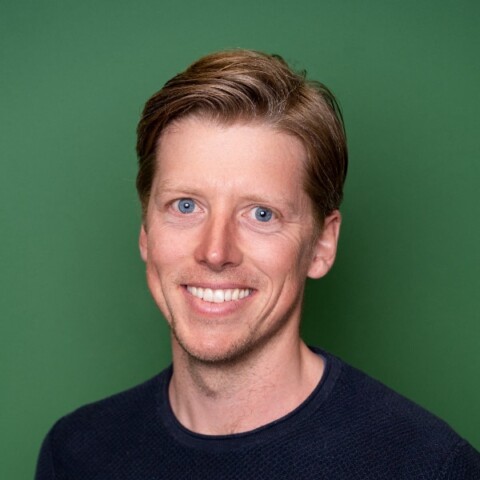 Studio portrait of author, sustainability expert Manuel Braun in front of a green background.