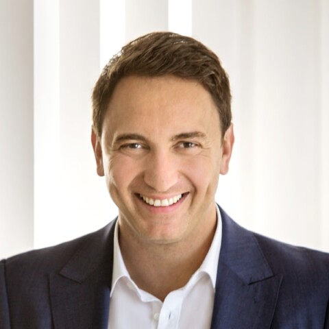 Headshot portrait of Mirko Mondan, CEO, Dorfner, in front of window blinds.