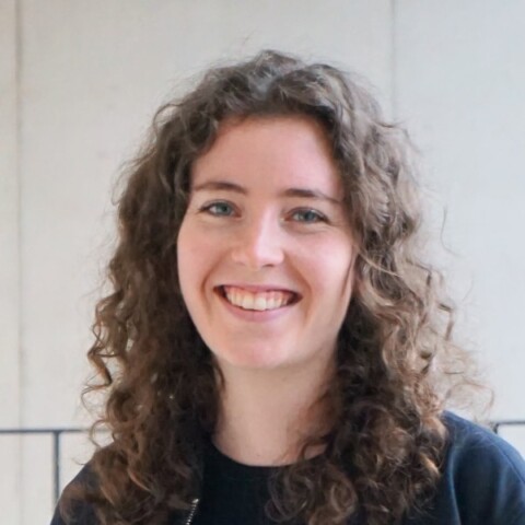 Environmental headshot portrait of Nicola Kolb, founder of Sitegeist Robotics, in front of a grey wall.