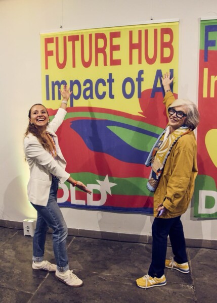 DLD founder Steffi Czerny and an attendee point to a yellow Future Hub poster