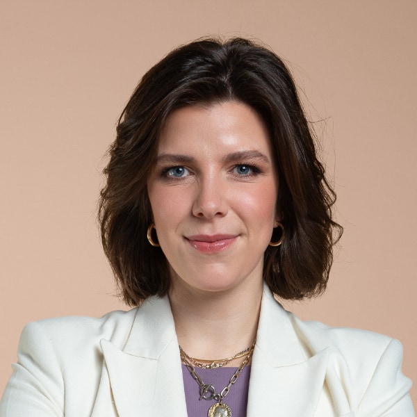 Headshot portrait of German journalist Rixa Fürsen, Politico, Welt TV, Axel Springer, in front of a beige studio background.