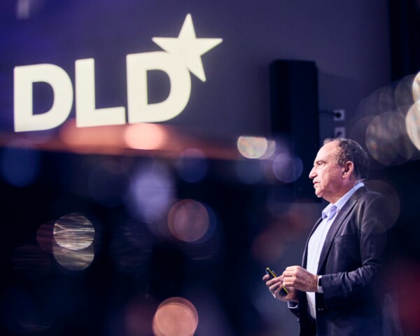 Yossi Matias, Head of Google Research, speaking at the DLD Future Hub conference in Munich, seen on stage from the side with the DLD logo visible in the background.