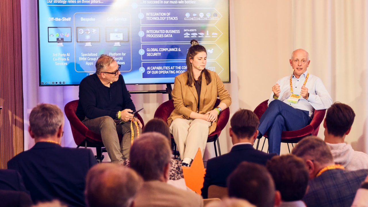 Christian Kirschniak (Boston Consulting Group BCG), Sarah Buerkle (SAP) and Michael Wuertenberger (BMW Group) in front of an attentive audience at the DLD Future Hub conference in Munich.