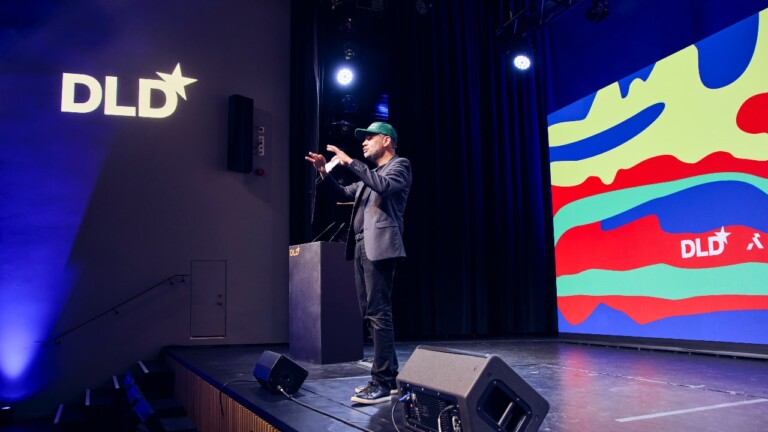 André Loesekrug-Pietri (JEDI) speaking at the DLD Future Hub conference in Munich, wearing a baseball cap with the motto “Make Europe Great Again”.