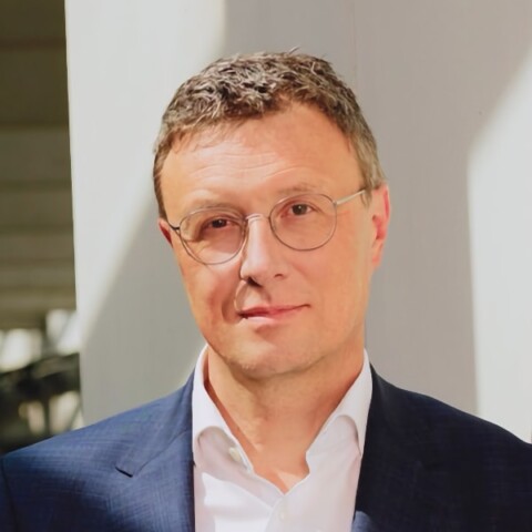 Headshot portrait of Patrick Cramer, Max Planck Society, in front of a grey wall.
