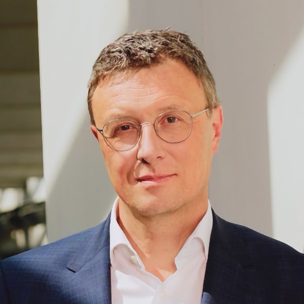 Headshot portrait of Patrick Cramer, Max Planck Society, in front of a grey wall.