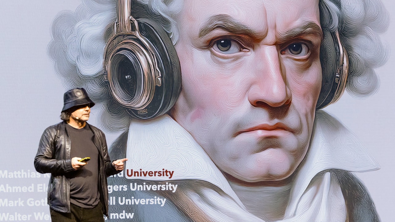 Walter Werzowa (HealthTunes) on stage at the DLD Future Hub conference in Munich, showing a poster-size image of Beethoven wearing headphones.