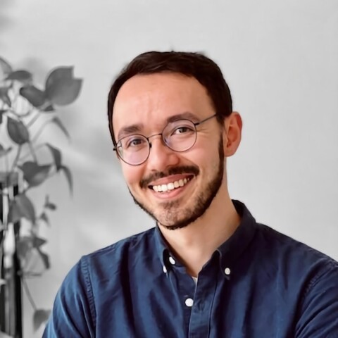 Environmental portrait of Yuki Asano, University of Nurember, sitting in a room with a behind him.