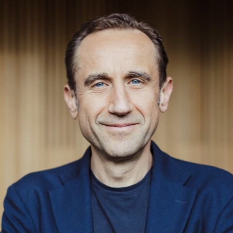 Portrait of Alessandro Centrone, head of Steelcase EMEA, in front of a wooden wall, smiling at the camera.