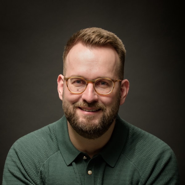 Studio headshot portrait of entertainment industry expert Bastian Bergmann, co-founder of Solsten, wearing a green shirt, brightly lit in front of a dark background.