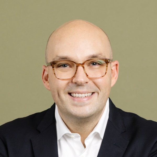 Headshot portrait of Justin Garcia, Executive Director of the Kinsey Institute, in front of an olive green studio background, smiling at the camera.