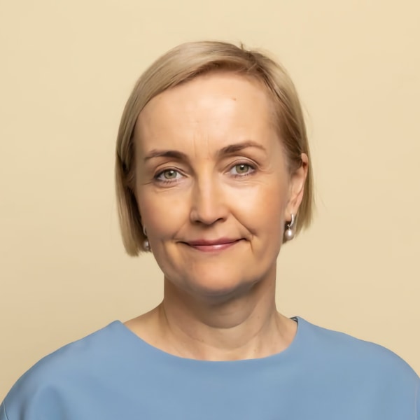 Headshot portrait of Estonian politician and educator Kristina Kallas in front of a light yellow studio background.