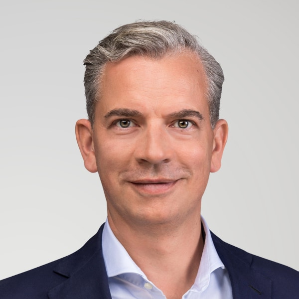 Headshot portrait of Matthias Voelkel, CEO of Börse Stuttgart Group, in front of a grey studio background.