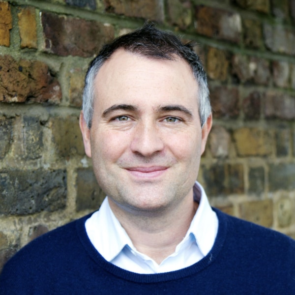 Environmental portrait of conservationist Ben Goldsmith, standing in front of a brick wall.
