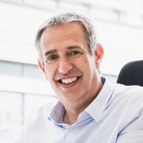 Portrait of German AI health researcher Prof. Daniel Rueckert, sitting in his office, smiling at the camera.