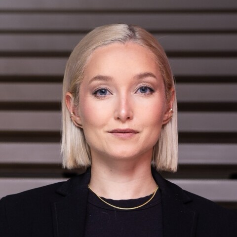 Headshot portrait of Politico podcast host Dasha Burns in front of black-and-white stairs.