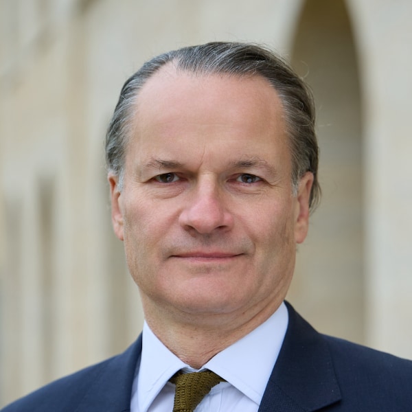 Headshot portrait of University of Oxford scholar Edward Harcourt, outdoors in front of a university building.