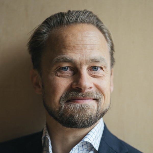 Portrait of Esben Gadsbøll, chairman of Danish Tech Startups, in front of a brown background.