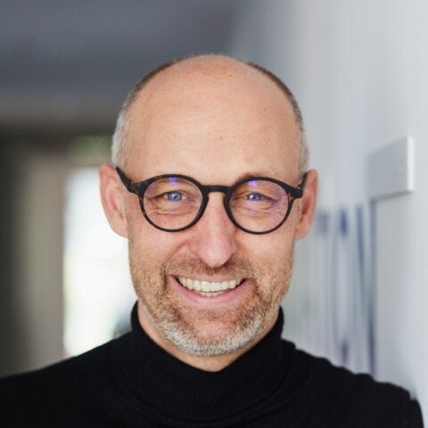 Headshot portrait of Frank Jackel, Metalshub, seen indoors, smiling at the camera.