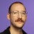 Headshot portrait of ZEIT journalist Jakob von Lindern in front of a purple studio background. Credit: Marzena Skubatz