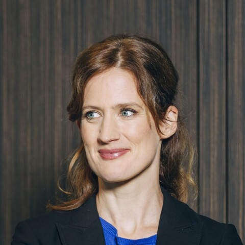 Portrait of German journalist Jennifer Wilton, smiling, looking to her right outside the frame.