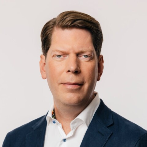 Headshot portrait of investor and entrepreneur Lars Hinrichs in front of a light grey studio background.