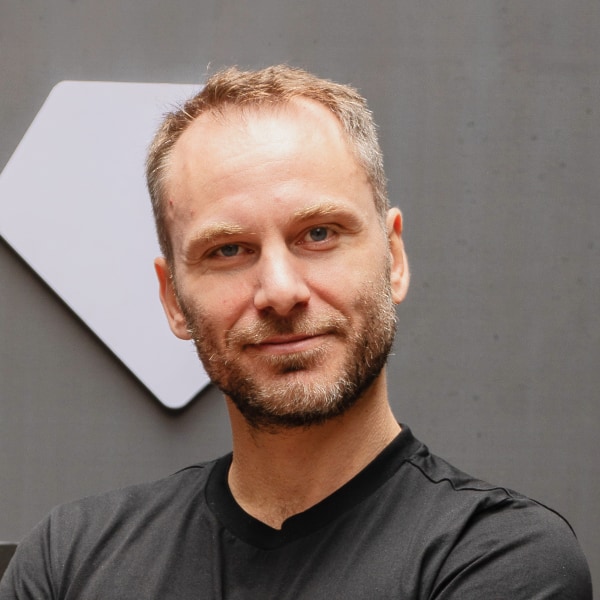 Headshot portrait of Tether CEO in front of a grey wall.