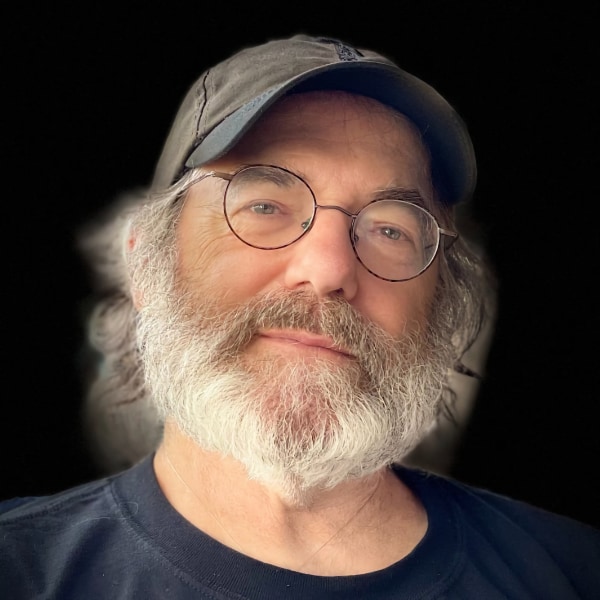 Headshot portrait of psychedelic mushroom expert Paul Stamets, brightly lit in front of a black studio background.