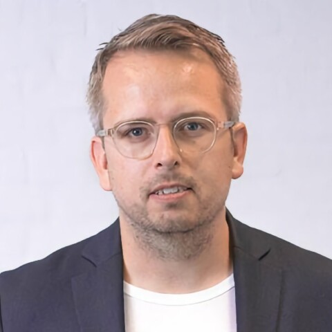 Portrait of Danish Internet pioneer Thomas Madsen-Mygdal in front of a light grey background.
