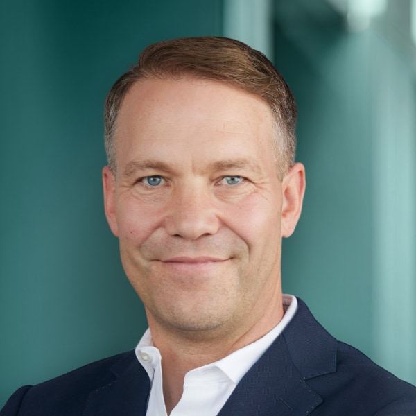 Headshot portrait of German venture investor Thomas Preuß, DTCP, in front of a blue background.