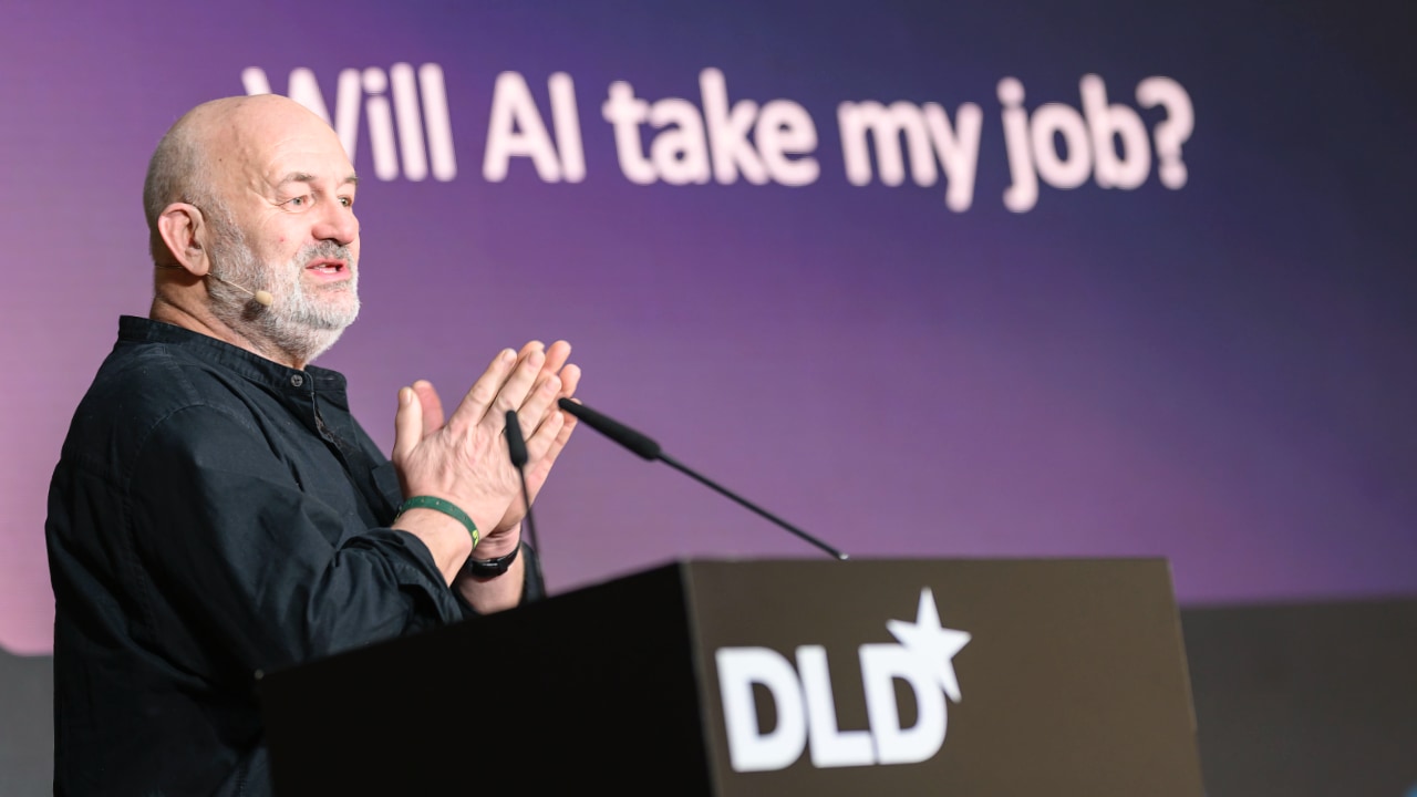 Amazon CTO Werner Vogels speaking at the DLD Munich 2026 conference. On a display behind him, a slide asks, “Will AI take my job?”
