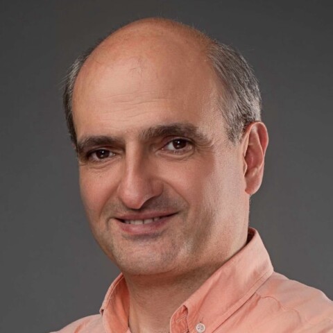 Headshot portrait of Armenian-British venture investor Yervand Sarkisyan in front of a grey studio background.