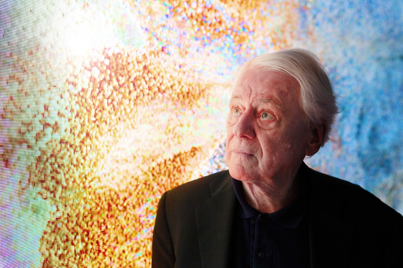 Portrait of late German philosopher Alexander Kluge in front of a colorful video installation. Credit: Mark William Fernandes