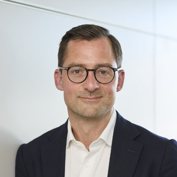 Headshot portrait of Maximilian Preisser, Hubert Burda Media, in front of a grey wall