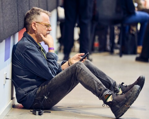 DLD conference attendee sitting on the floor, charging his phone, reading