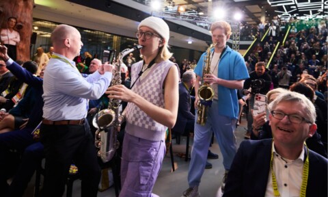 Munich band Knallblech walking through the audience at the DLD Munich 2026 conference, playing saxophone