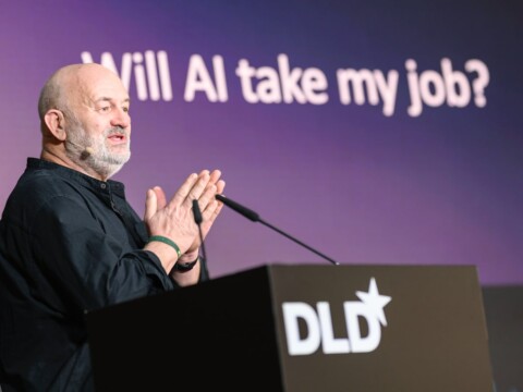 Amazon CTO Werner Vogels speaking at DLD with a slide behind him showing the question, “Will AI take my job?”