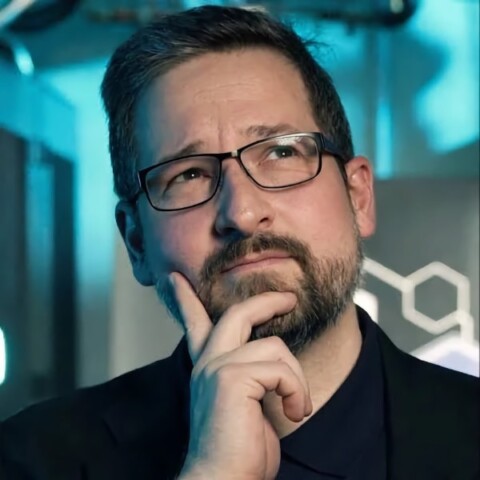 Headshot portrait of medical imaging expert Bernhard Kainz, looking pensive in front of a blue-gray background.