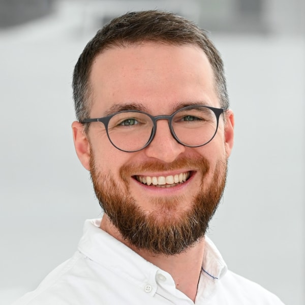 Headshot portrait of Florian Hinterwimmer, AI health researcher at TU Munich and co-founder of SciEspresso, in front of a grey background.