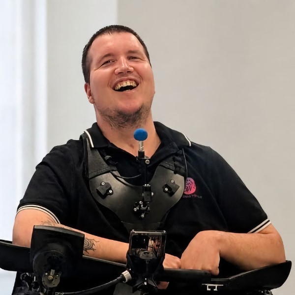 Image of Michael (Michi) Mehringer sitting in a wheelchair, smiling. Photo credit: Heidi Willmann