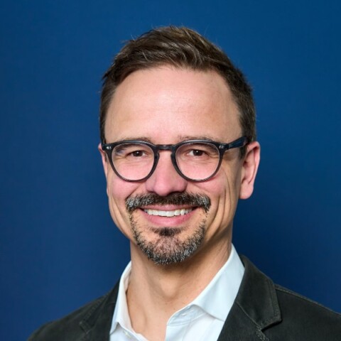 Portrait of Nils Hesse, BMW Group, in front of a dark blue studio background