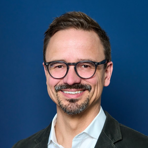 Portrait of Nils Hesse, BMW Group, in front of a dark blue studio background