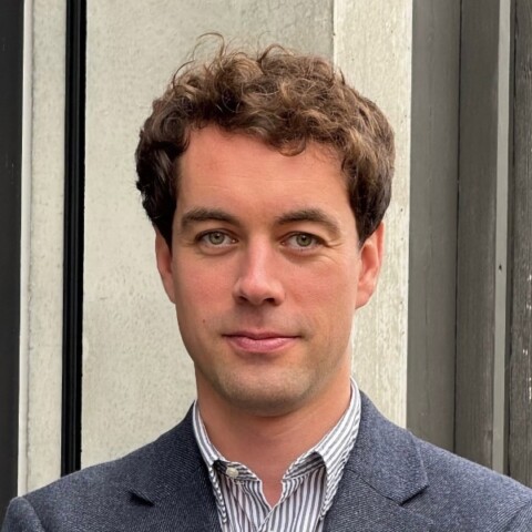 Environmental portrait of TUM researcher Georg Starke in front of a grey wall