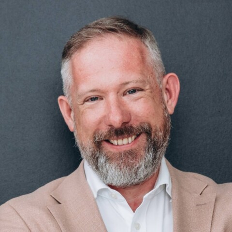 Headshot portrait of Roland Bruns, CIO at German health insurance company BARMER, in front of dark grey studio background