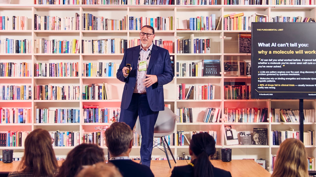 Hajo Schiewe (SandboxAQ) speaking at DLD Health x BAIOSPHERE conference, standing in front of bookshelves at Literaturhaus Munich, addressing the audience, on June 12, 2026. Photo: Dominik Gigler for DLD / Hubert Burda Media